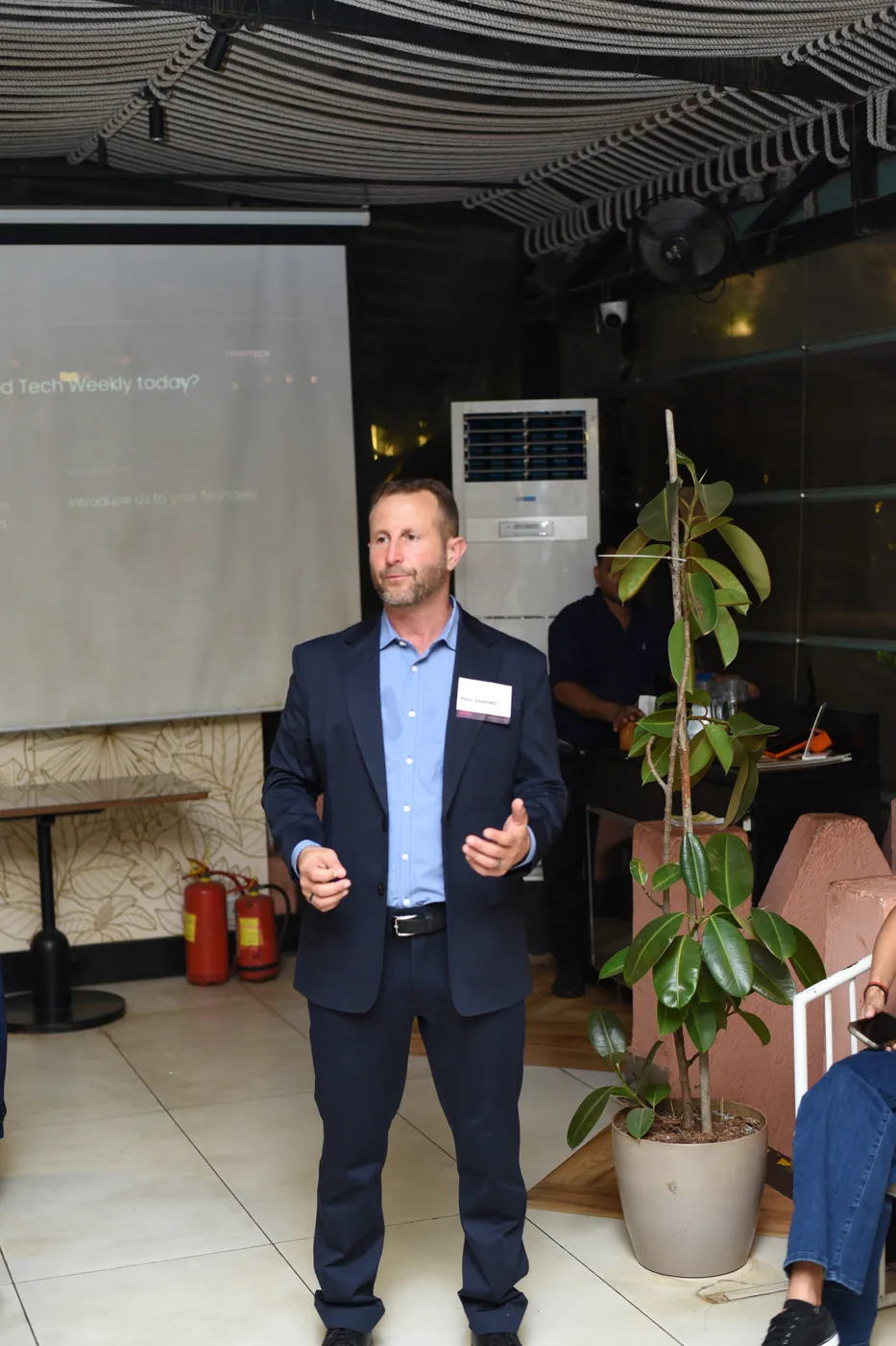 Paul Shapiro speaking at the FoodTech Weekly Roadshow in Mumbai, navy blazer, nametag